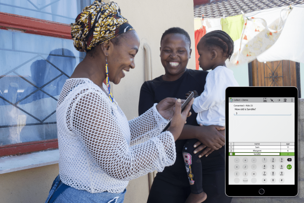 Image of a woman using a mobile tablet to interview another woman, who is holding a child. The photo is from SurveyCTO's photo shoot in Capetown, South Africa.