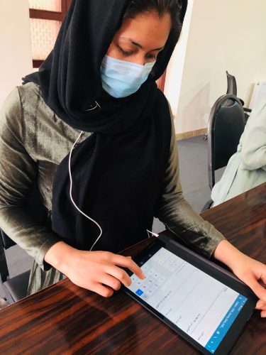 community_health_work A woman in a medical mask uses SurveyCTO on a mobile device.
