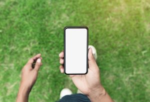 man holding phone showing blank screen walking on lawn