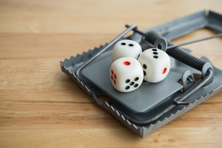 White three casino dice gambling in rat trap on wooden background with copy space. Gambling, betting online casino, social problem, investment in stock market concept.