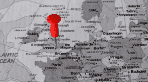 A black and white image of a map of Europe, with a red pin to identify London, United Kingdom.