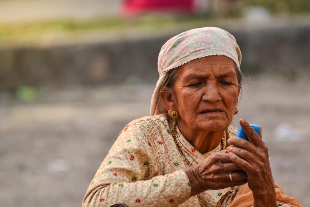 An elderly woman in Nepal explores a mobile device.