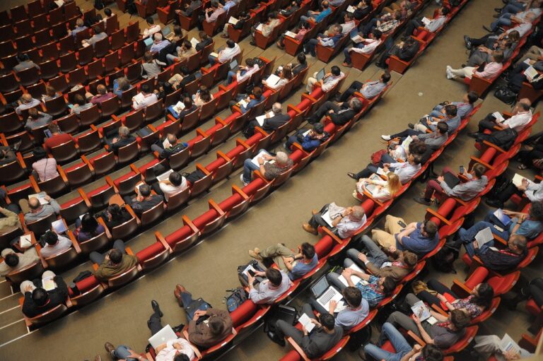 Attendees at a conference sit in an auditorium.