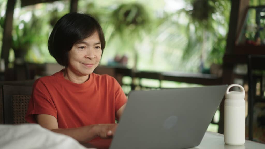 Asian woman working on laptop at nature resort.